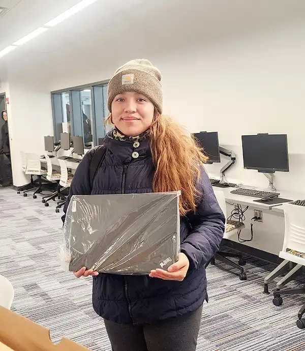 Bridge Program student holding a laptop prize that she has won