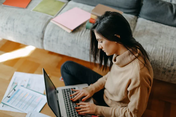 Picture of woman working on computer surrounded by paper materials