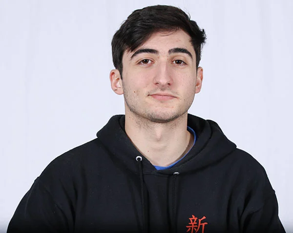 Male student with black hair wearing a dark colored hoodie.